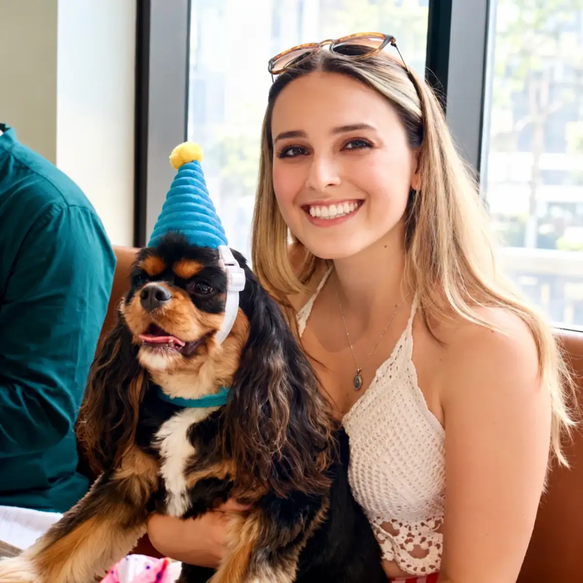 Un cavalier King Charles avec chapeau de fête et une cliente souriante au Ruby Café MTL